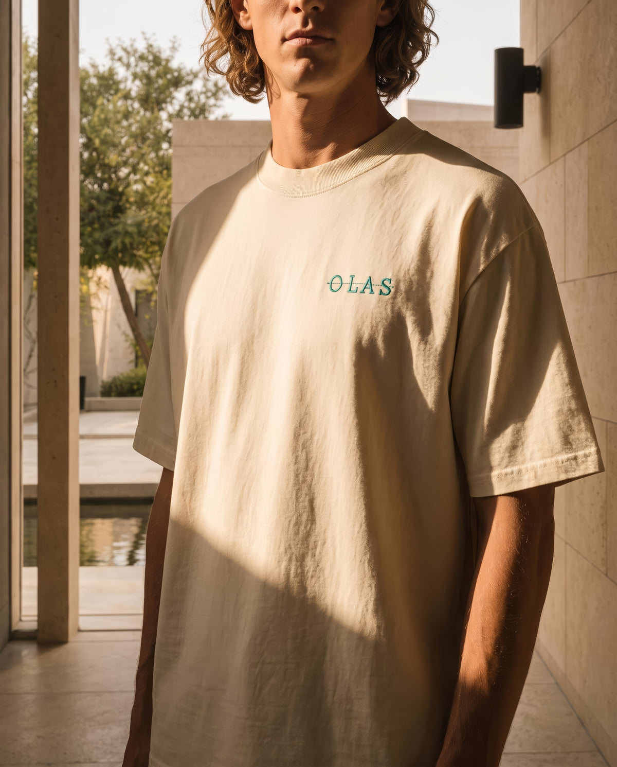 Close view of the embroidered OLAS mark on the chest in raking afternoon light