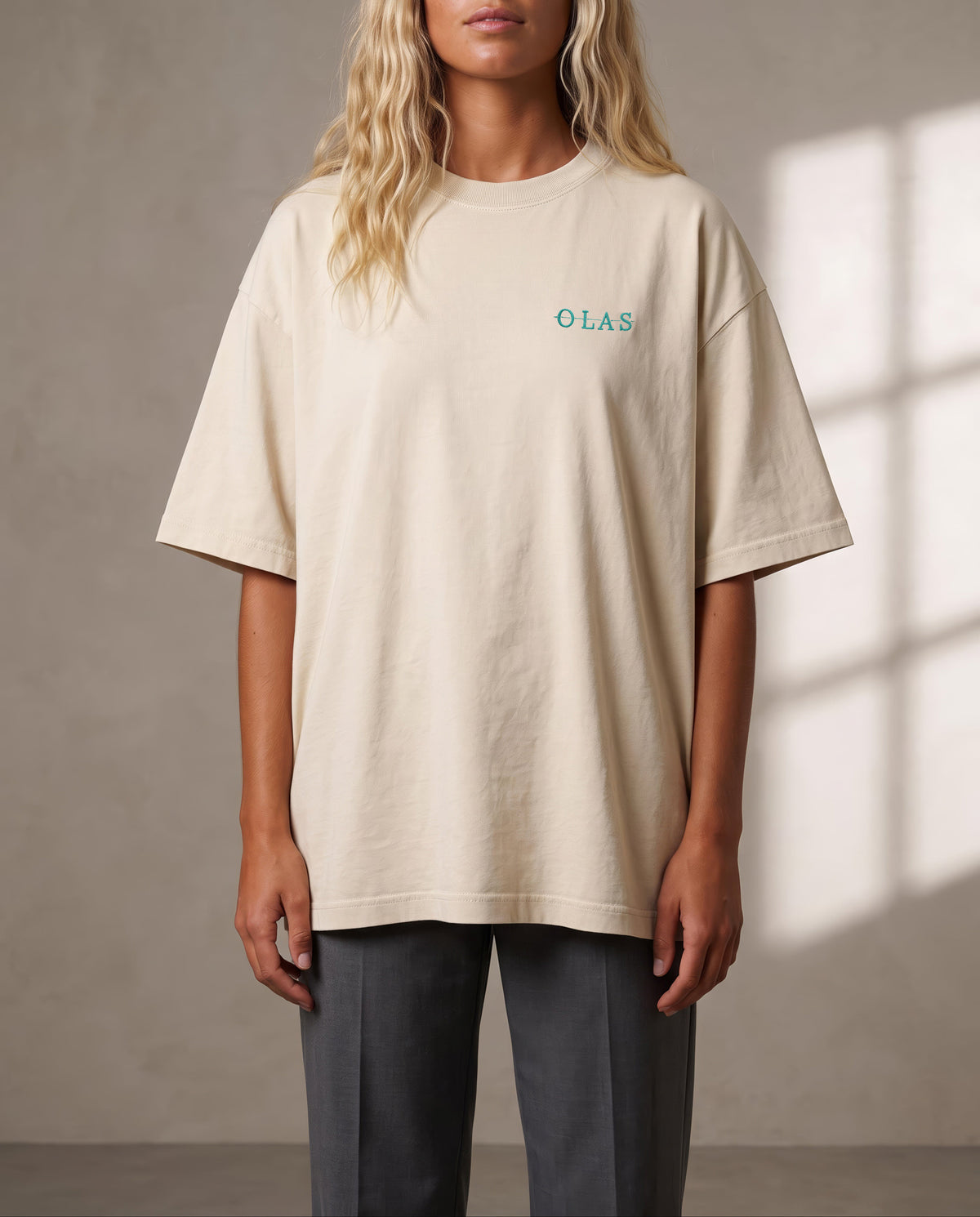 Front of the cream tee on the body, with the embroidered OLAS mark at the left chest