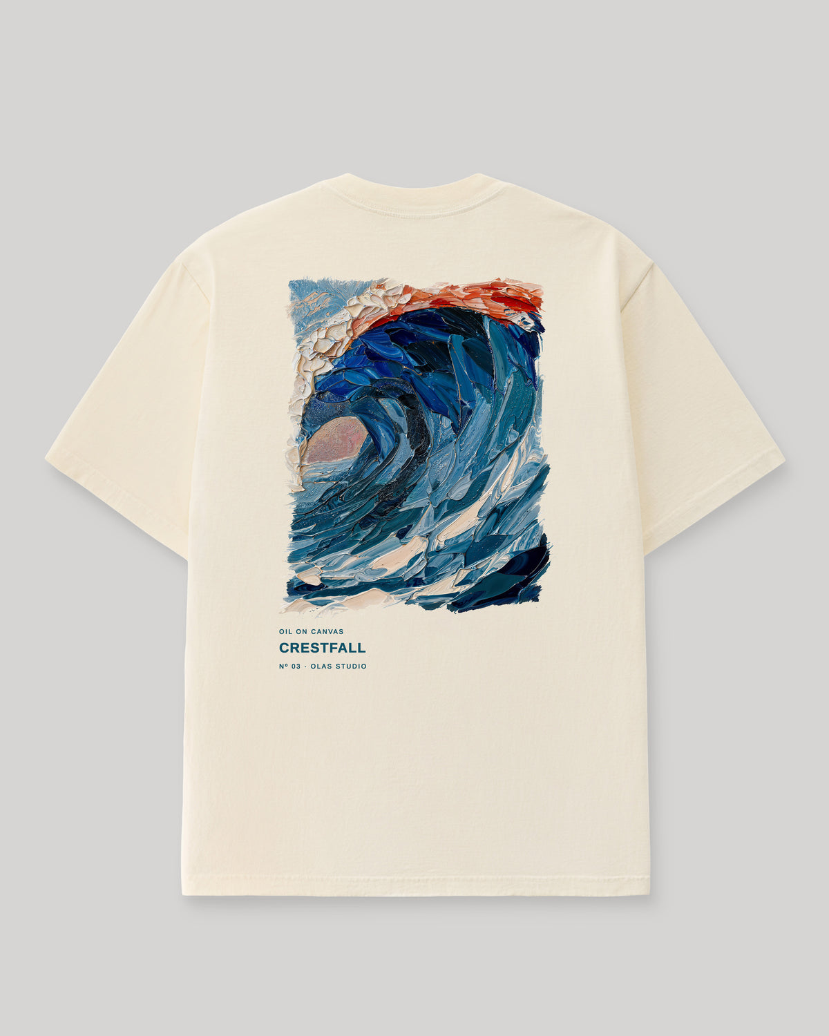 Back of a cream Olas Studio T-shirt with Crestfall: a curling blue wave with a cream-white crest and a narrow red edge.