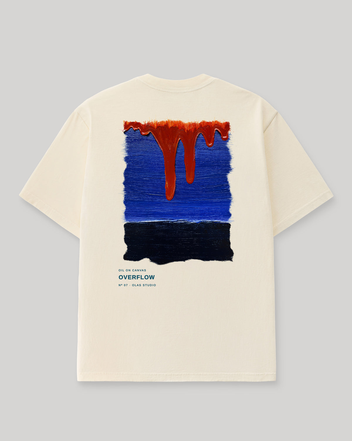Back of a cream Olas Studio T-shirt with Overflow: orange-red drips descending into cobalt blue above a near-black band.