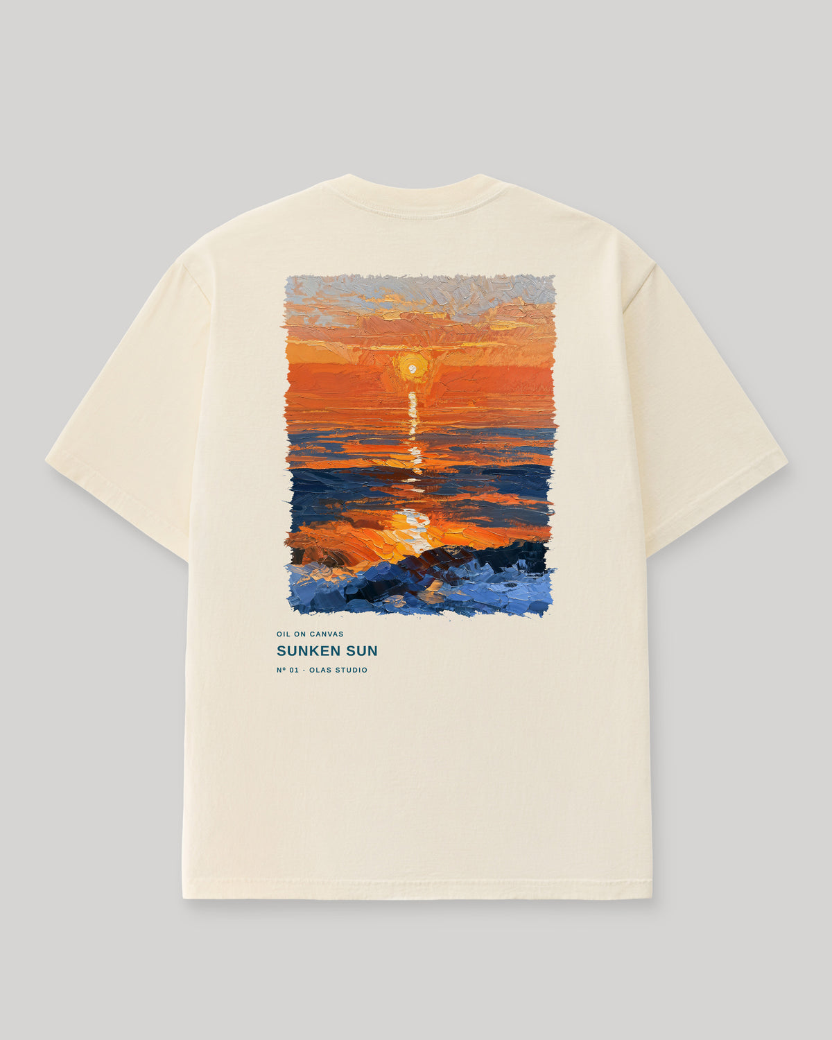 Back of a cream Olas Studio T-shirt with Sunken Sun: an orange sun above layered orange and deep-blue bands, with a bright reflection reaching dark rocks.