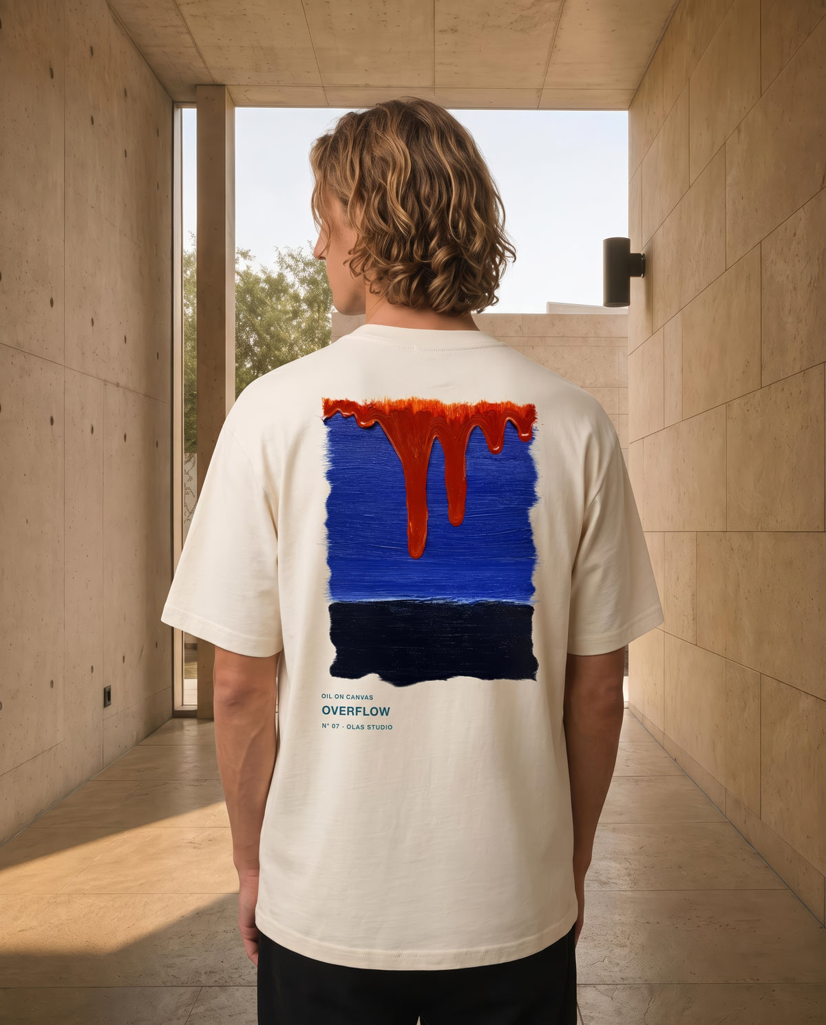 A model in a stone doorway, the Overflow work across the back of the tee